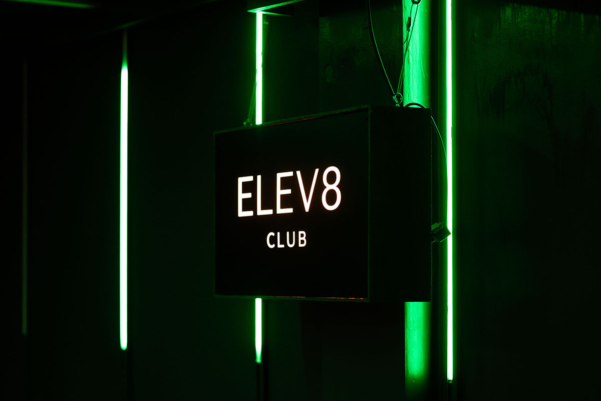 Elev8 club sign lit in green neon